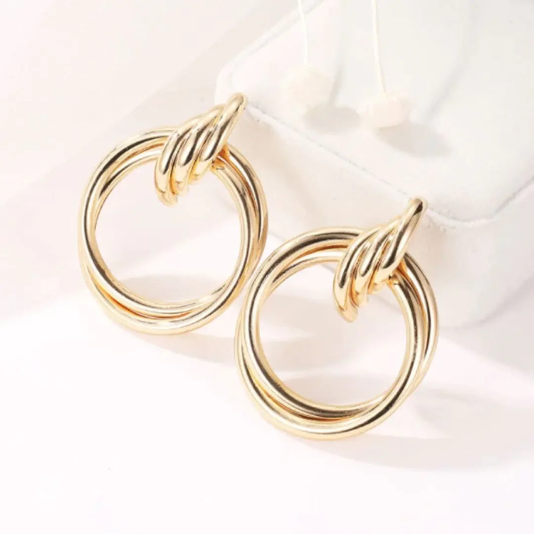 Elegant gold double hoop earrings displayed on white jewelry pouch, sleek and timeless design