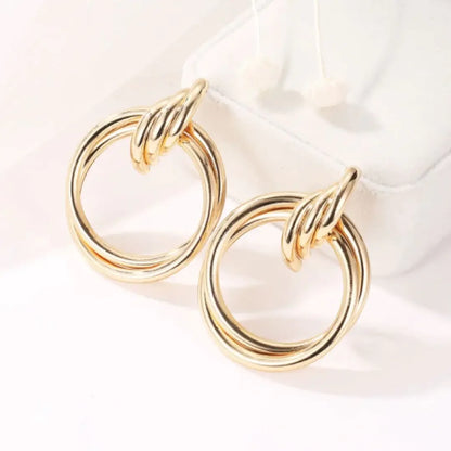 Elegant gold double hoop earrings displayed on white jewelry pouch, sleek and timeless design