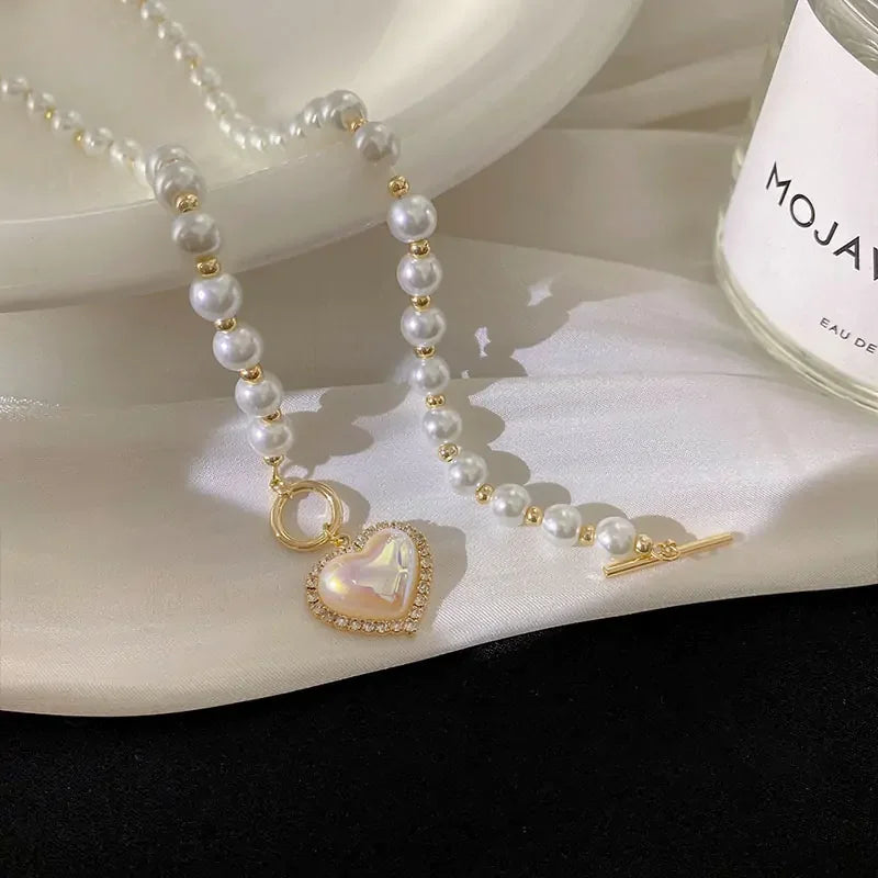 Elegant pearl necklace with gold accents and heart-shaped pendant on satin surface