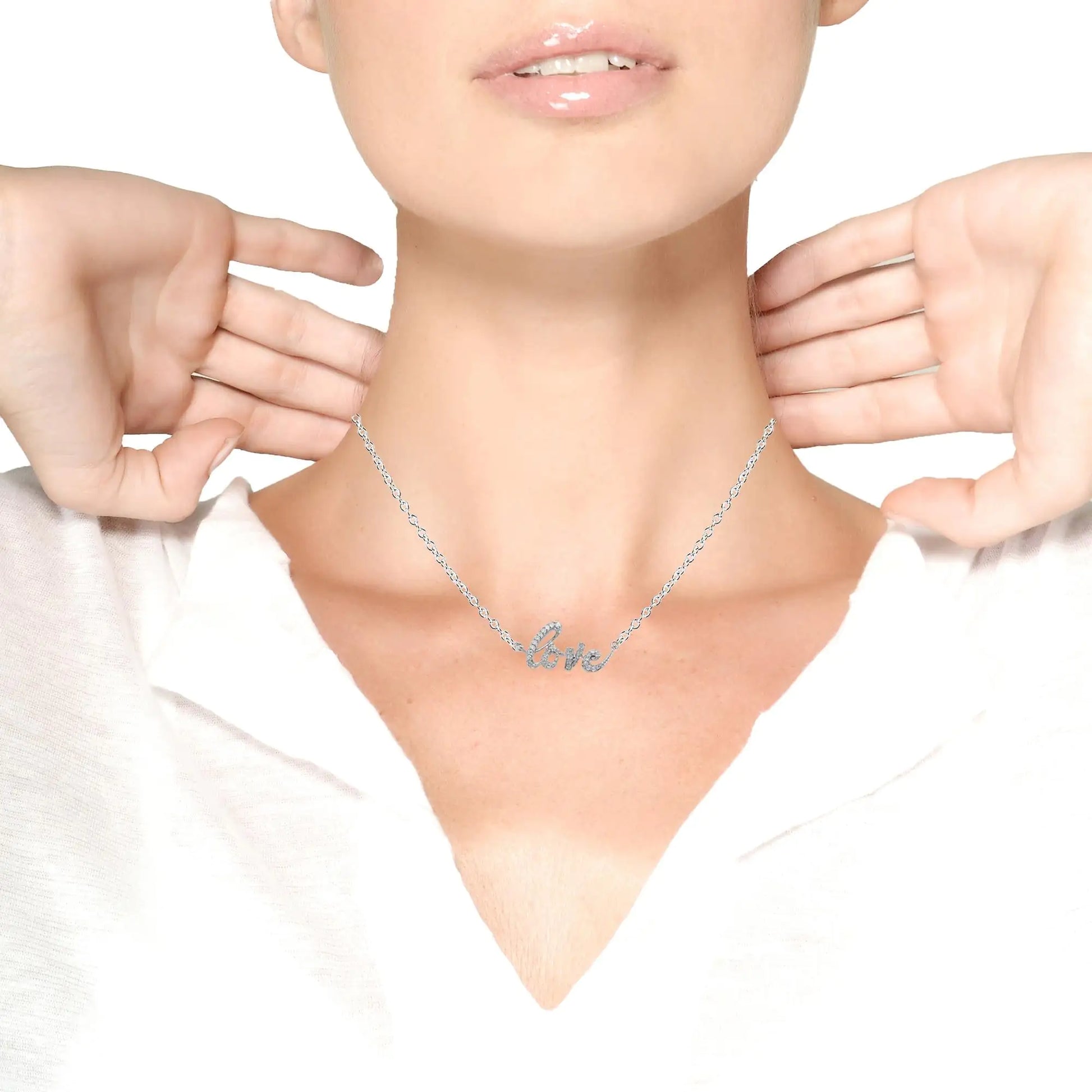 Woman wearing silver necklace with diamond-studded 'love' pendant on white background