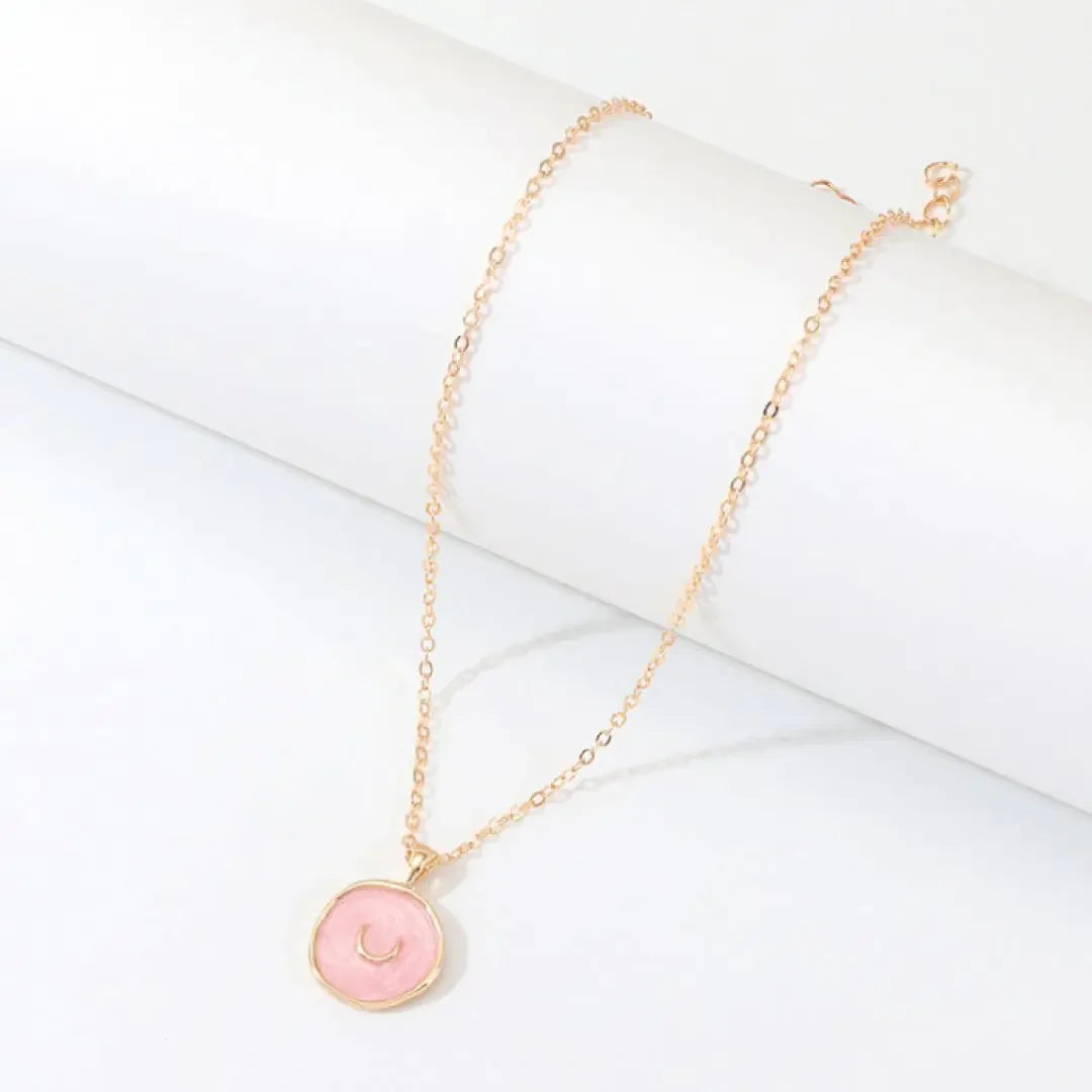 Elegant gold chain necklace with round pink pendant featuring a crescent moon design