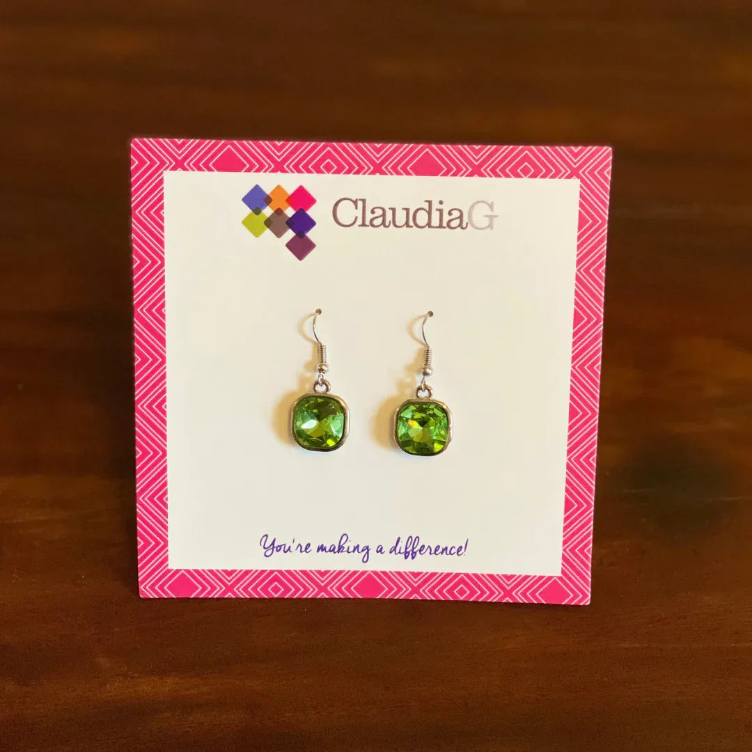 ClaudiaG green gemstone dangle earrings displayed on branded card with pink border on wooden surface