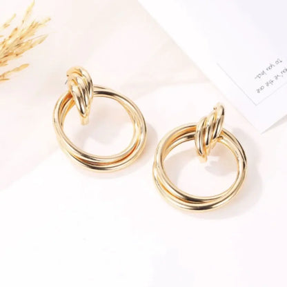 Pair of elegant gold hoop earrings with twisted top design on white surface