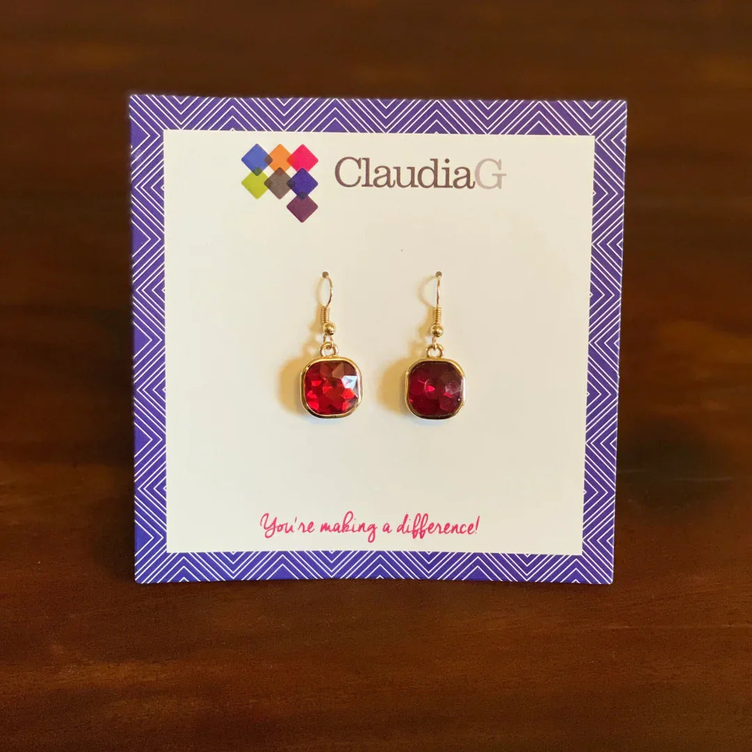 ClaudiaG red gemstone dangle earrings on branded card with purple border, displayed on wooden surface