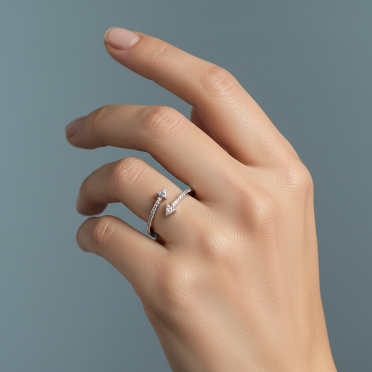 Hand wearing a silver arrowhead ring with embedded stones on a sage green background, elegant fine jewelry