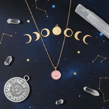 Astral gold necklace with moon phases and pink pendant on starry constellation background with crystals