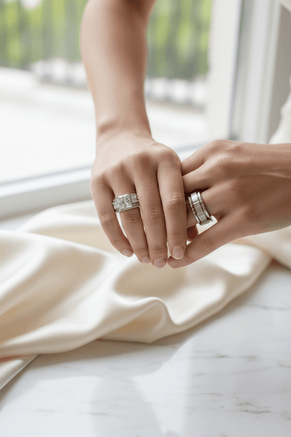 Close-up of couple holding hands wearing elegant matching silver rings on a soft fabric background