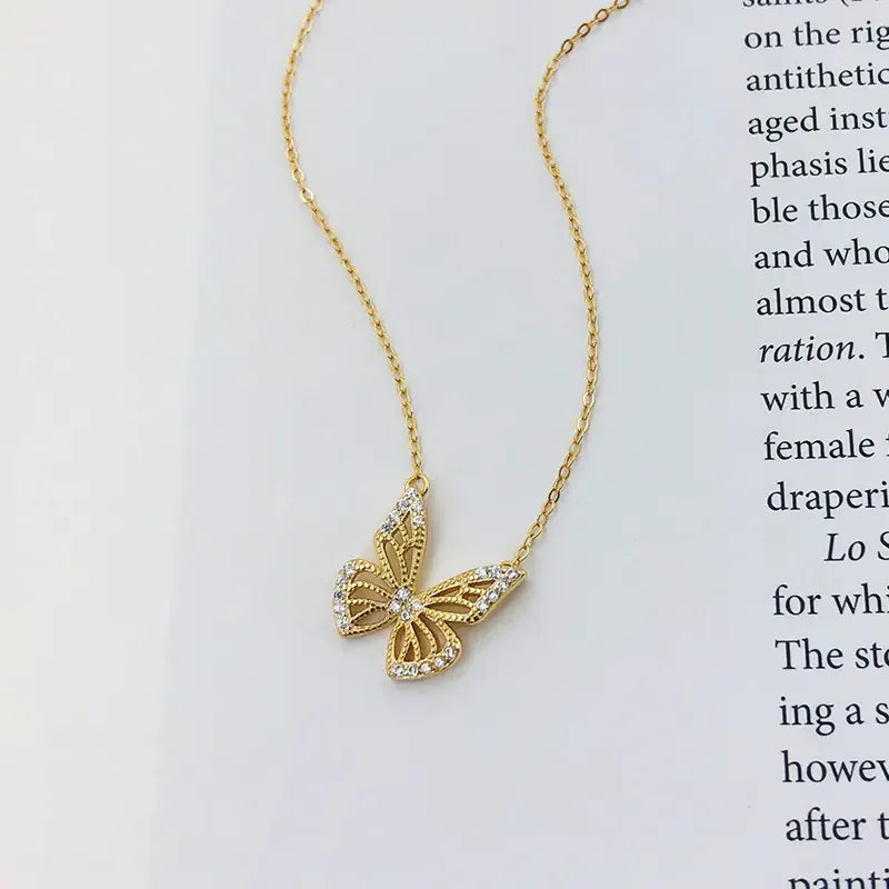 Elegant gold butterfly pendant necklace with crystal accents on white background with printed text