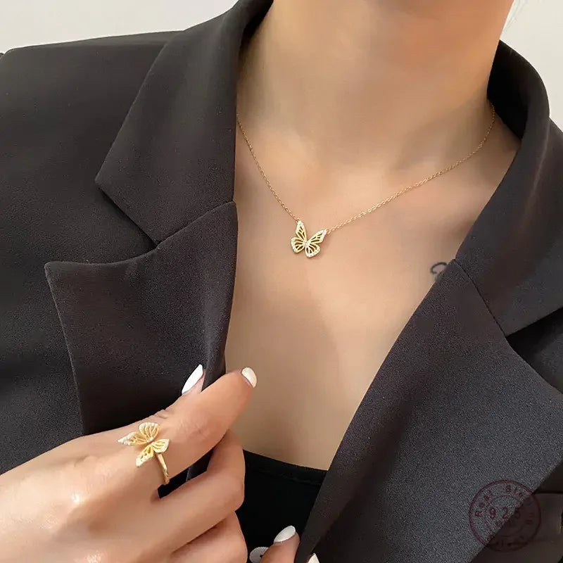 Gold butterfly pendant necklace and matching ring worn with black blazer for elegant fine jewelry look