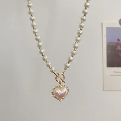 Elegant pearl necklace with gold beads and a heart-shaped pearl pendant embellished with crystals