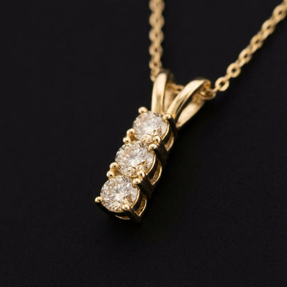 Gold necklace with three round sparkling diamonds pendant on black background