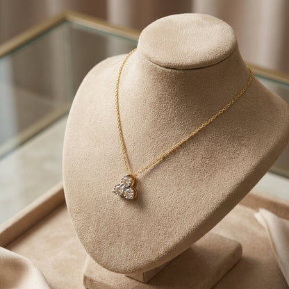 Gold chain necklace with a three-circle diamond pendant displayed on a beige velvet jewelry bust
