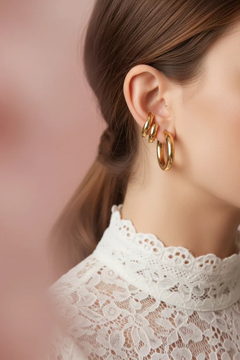 Close-up of elegant gold huggie hoop earrings on woman wearing white lace top