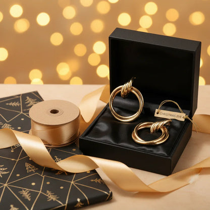 Gold statement earrings in black gift box labeled Christmas Eve with gold ribbon and festive wrapping