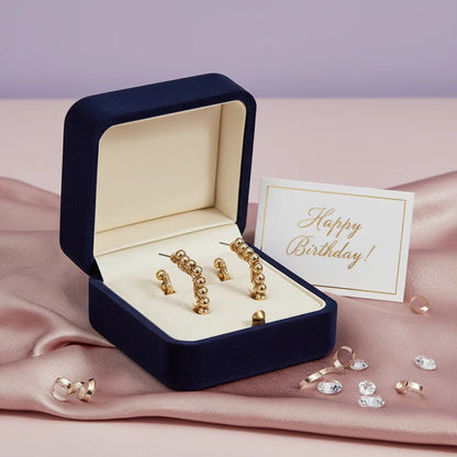 Gold textured hoop earrings in a navy velvet gift box with Happy Birthday card on pink satin