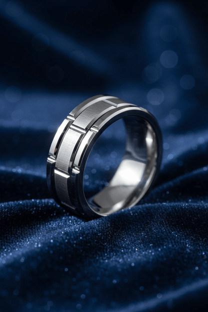 Close-up of a modern silver men's wedding band with geometric design on dark blue velvet