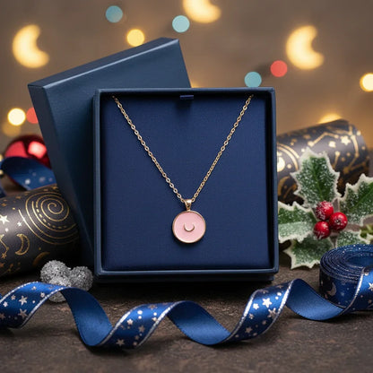 Gold moon pendant necklace with pink enamel in a navy blue gift box, holiday decor background