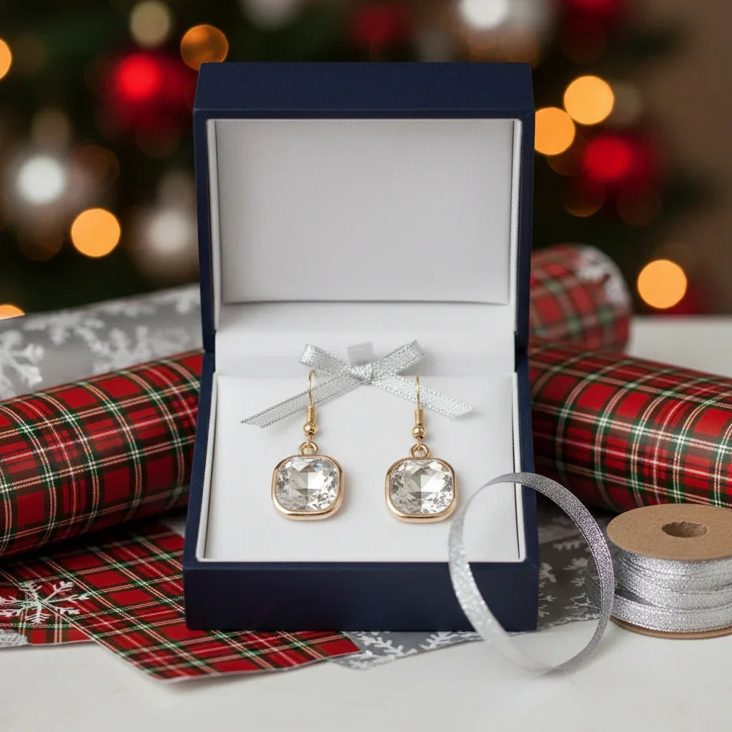 Square crystal drop earrings with gold trim displayed in a blue gift box, festive plaid wrapping paper and silver ribbon