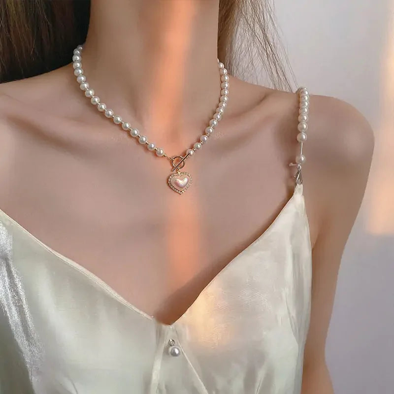 Close-up of woman wearing pearl necklace with heart pendant and satin camisole with pearl strap detail