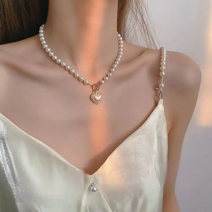 Close-up of woman wearing pearl necklace with heart pendant and satin camisole with pearl strap detail
